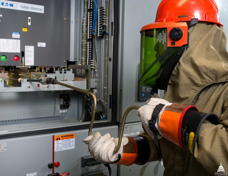 High-voltage electrician Da'suan Mason follows precise procedures and wears a fireproof 40 cal arc flash suit while performing regular preventive maintenance on a 15,000 volt circuit.