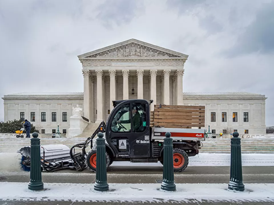 A member of the U.S. Capitol Grounds and Arboretum team clears snow in front of the Supreme Court Building.