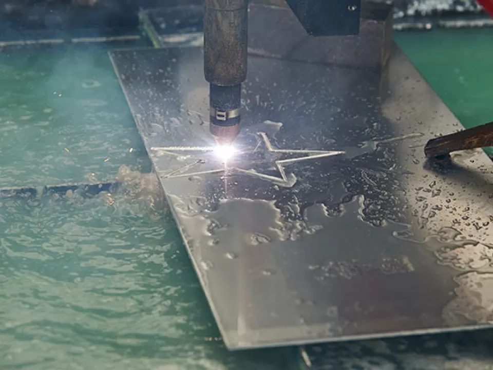 Sparks fly as the plasma torch cuts a star out of an aluminum sheet.
