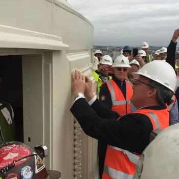 Group of people wearing safety vests and hard hats.