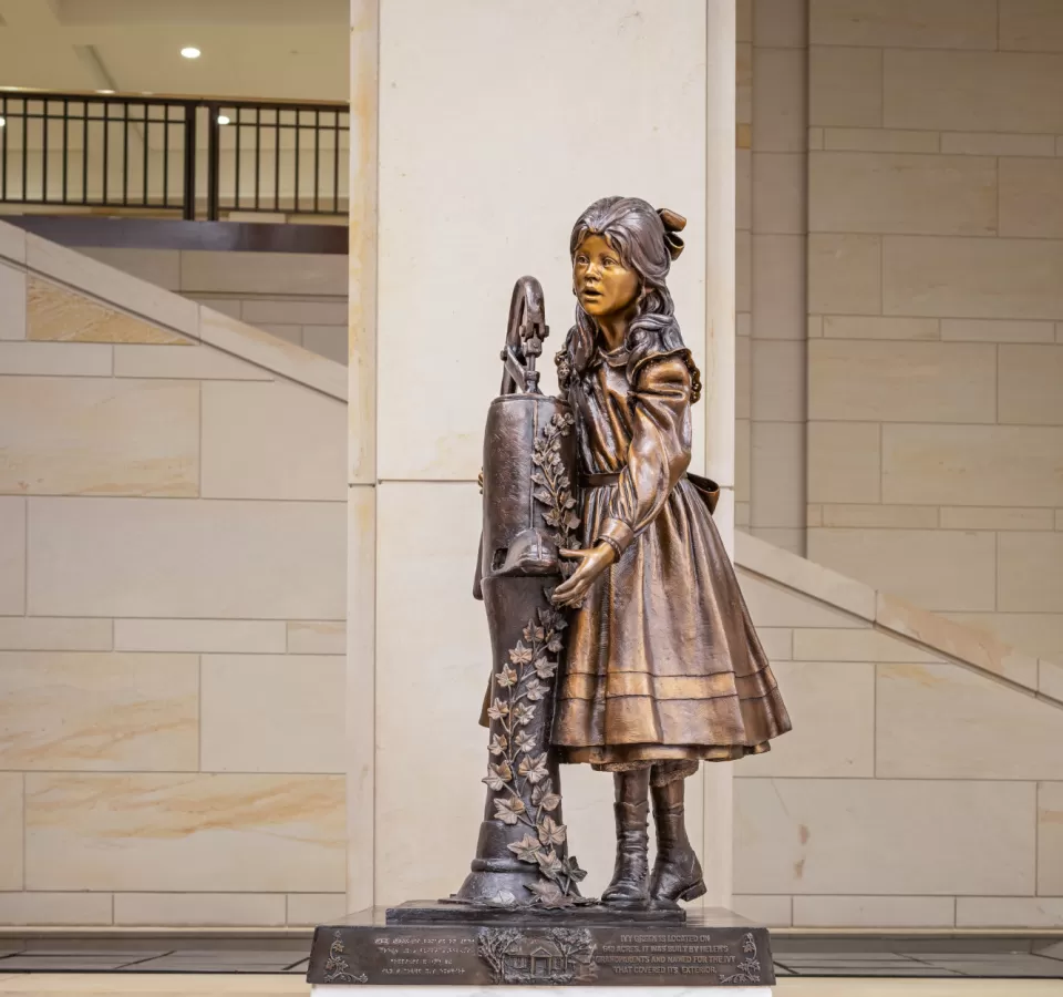 Bronze statue of child standing.