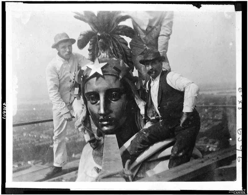 Architect of the Capitol employees take a self-portrait (note string in hand of individual all in white) while preserving the Statue of Freedom in 1913.