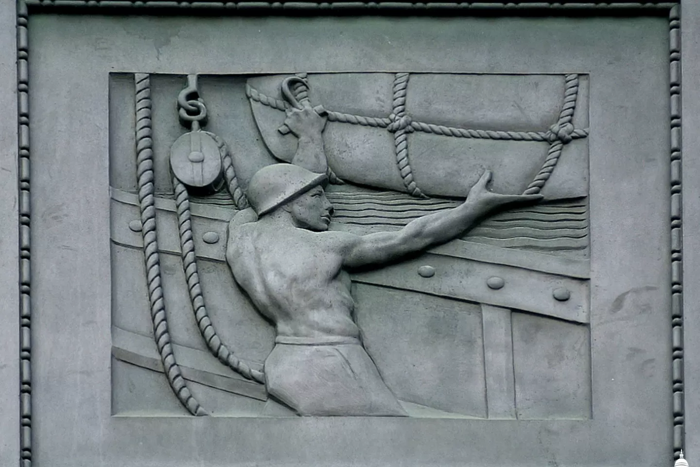 A sailor maneuvers cargo in a panel on exterior of the Dirksen Senate Office Building. 