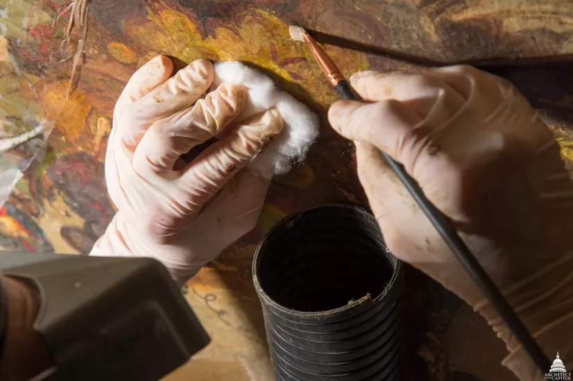 Hands working on a painting.
