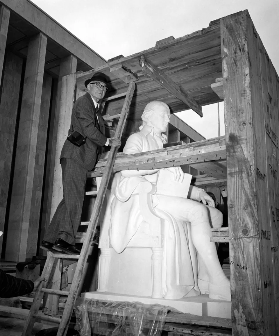 Sculptor Walker Hancock examines the James Madison statue when it was delivered in 1976. The sculpture is carved of Carrara marble.