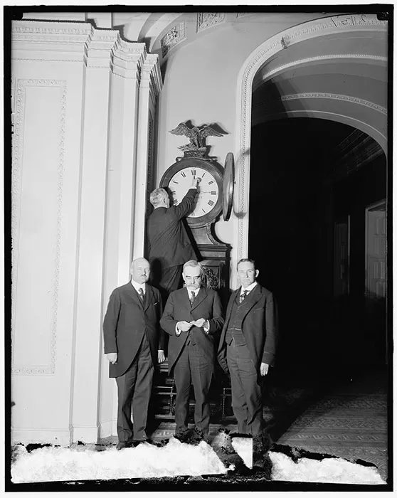 Senate Sergeant at Arms Charles Higgins turns forward the Ohio Clock for the first Daylight Saving Time, while Senators William Calder (NY), William Saulsbury, Jr. (DE), and Joseph T. Robinson (AR) look on, 1918.