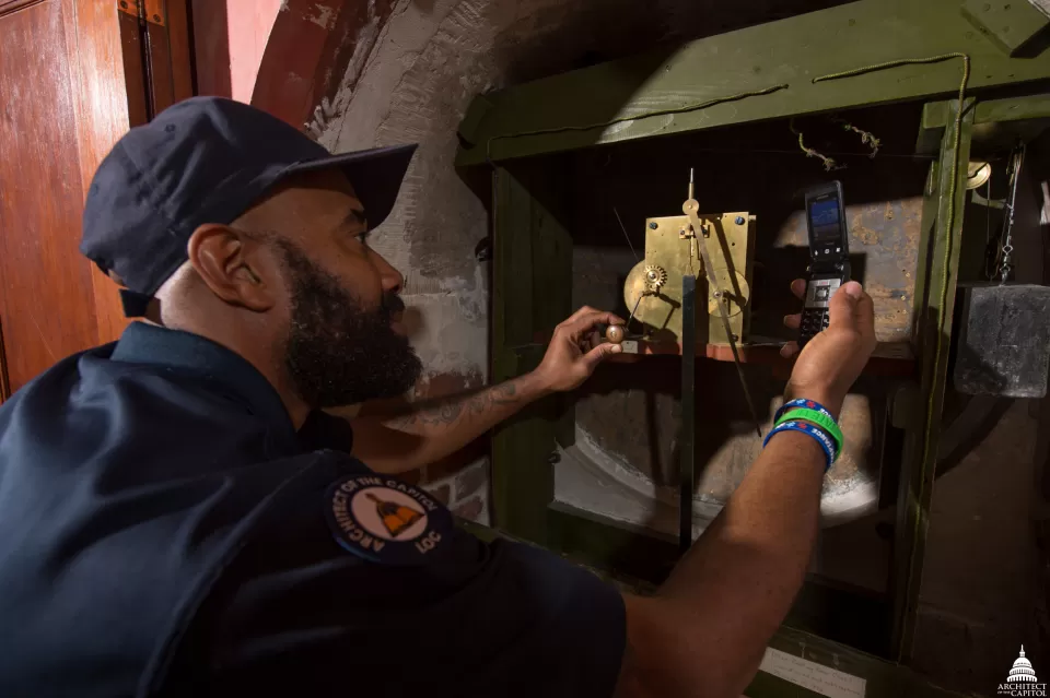 An AOC Library Buildings and Grounds Electrician sets the Flanagan clock.