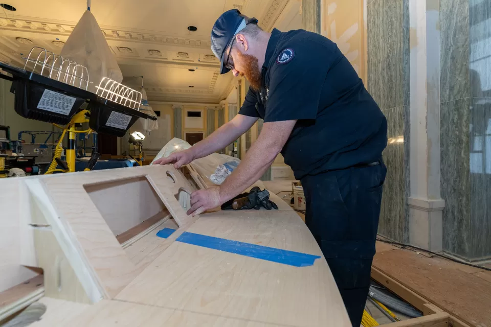Matt Flechner, woodcrafter leader with the Senate Woodcrafting Branch, installs a 14-inch monitor, microphone and touchscreen control panel for each senator into the dais, making sure the equipment doesn't impair the sight line of committee members during hearings.