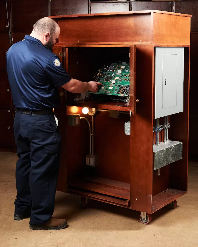 Greenwell points out the fire alarm control boards; underneath are the light bulbs and electrical switches that children played with during Take Your Child to Work Day.