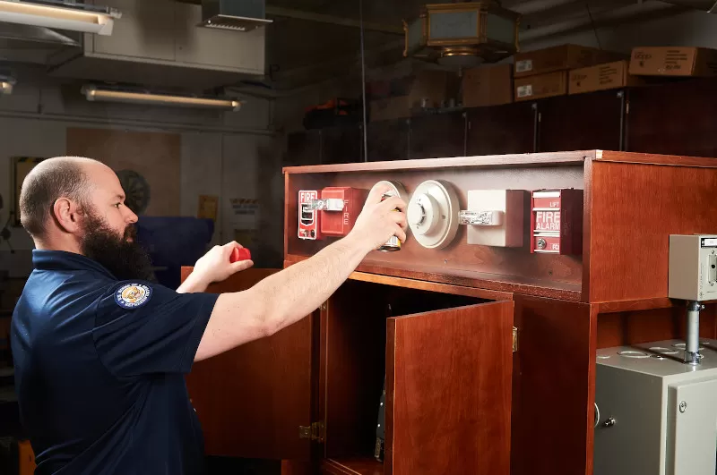 Greenwell sprays a can of smoke on one of the fire alarms to set it off.