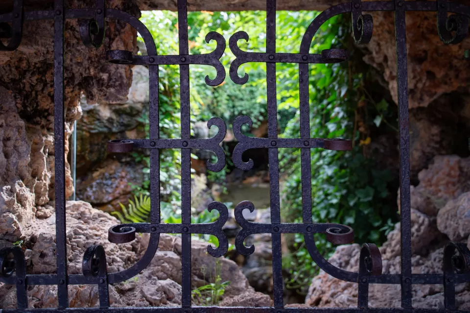 The view through the wrought-iron window grate into the lush overgrown grotto of the Summerhouse.