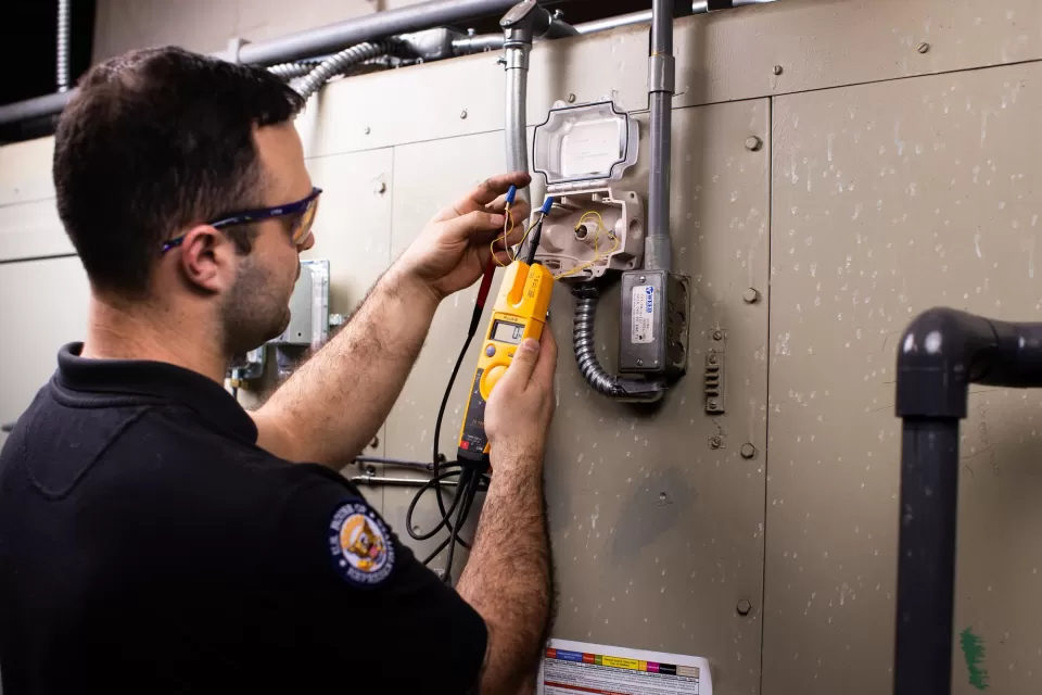 A/C Equipment Mechanic Justin Zibragos tests temperature sensor function using an electrical tester.