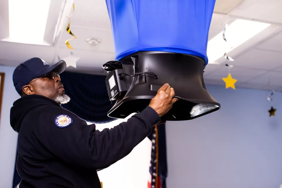 A/C Equipment Mechanic Kerian Ozurumba takes airflow readings from a vent using a balometer.