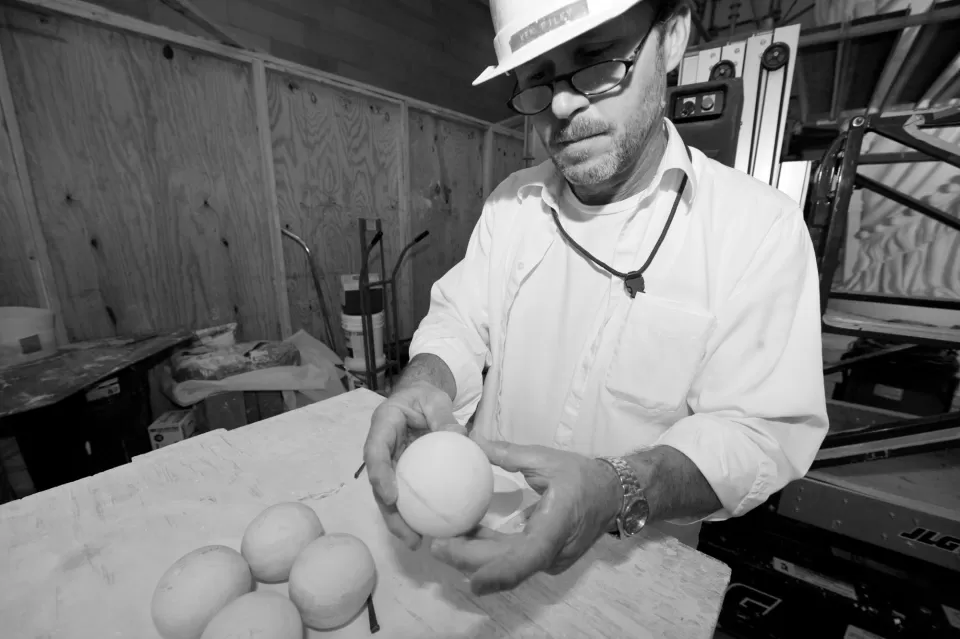 Person wearing a hardhat holding a round object.