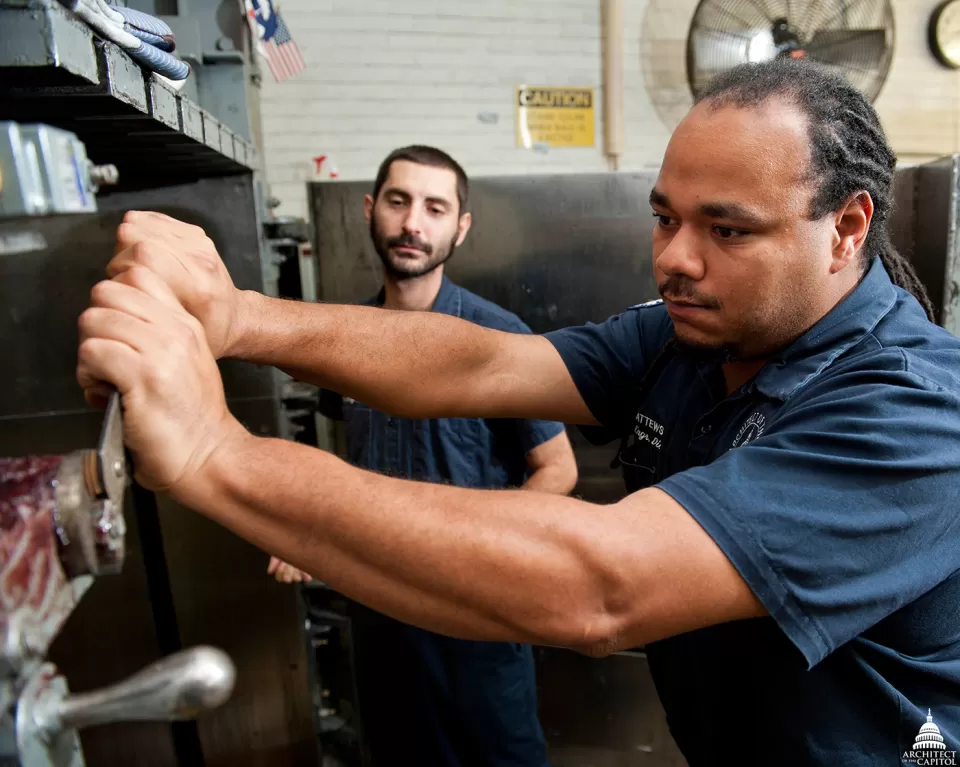 Industrial Mechanics Jeff Weiskott and Derek Matthews perform maintenance on the cardboard baler to ensure its continued function.