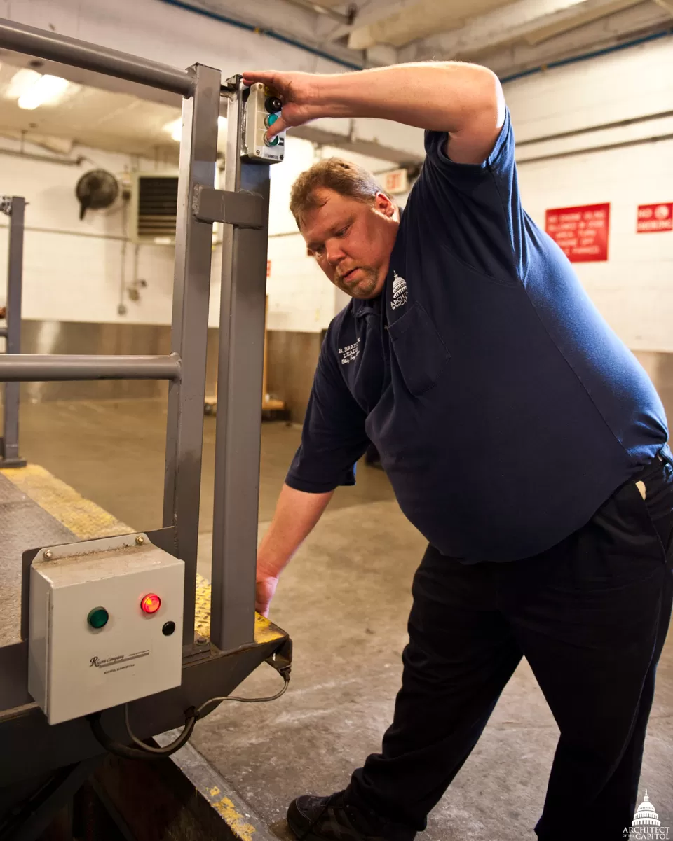 Industrial Mechanic Equipment Leader Brian Bradley tests the pressure switch on the loading dock leveler in the Rayburn Building.