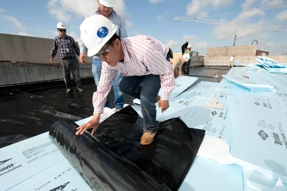 Workers installing a filter fabric over a drainage layer on the Dirksen Building roof.