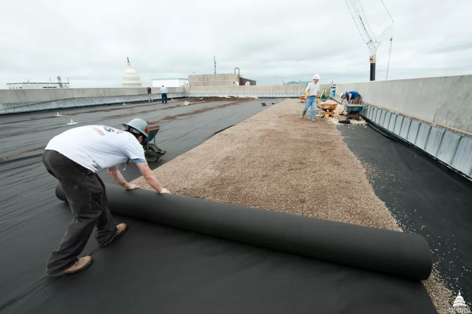 Workers installing a rigid insulation over the Dirksen Building root barrier, creating two inches of insulation.