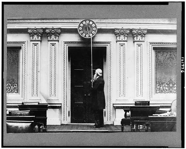 Doorkeeper Isaac Bassett adjusts Senate Chamber clock.