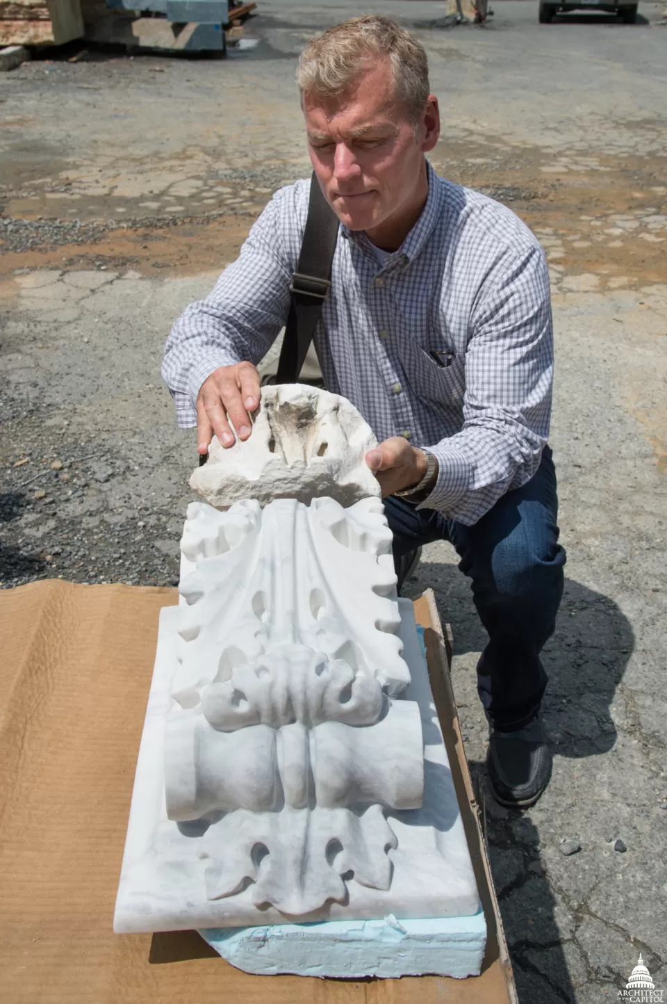 Project Manager Chris Lear compares an original, weathered stone carving with a newly carved replacement.