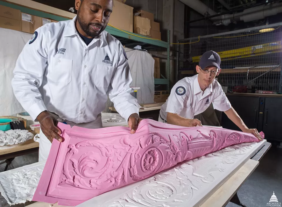 Abraham (A.J.) Jackson and Robert Gannon remove a mold from a plaster cast as part of historic preservation work in the Russell Building.