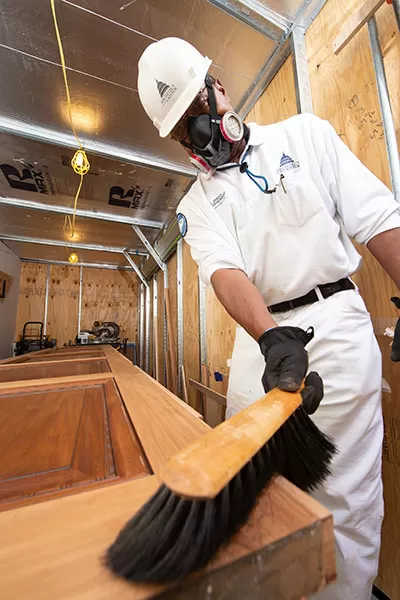 Painter/re-finisher prepping the door surface for stain after the old hinge locations were filled and sanded.