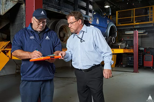 Stevan Boozer (left) and Lee Dennis (right) check the paperwork on a recently inspected vehicle.