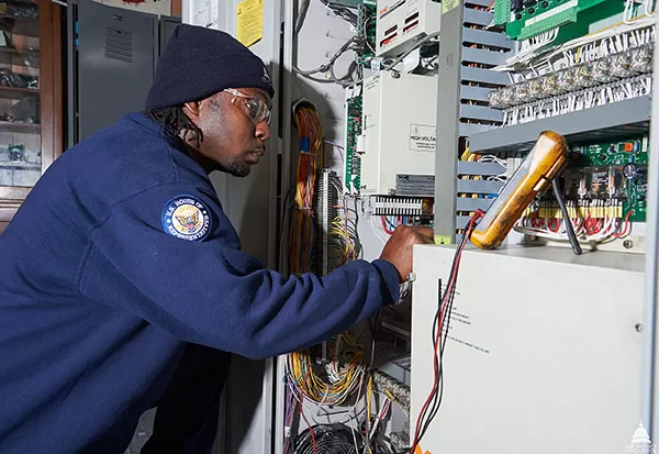 Alleyne uses a multimeter to diagnosis a problem with an elevator controller. 