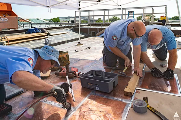 Members of AOC's Sheet Metal Shop solder and install flat seam copper roof panels.