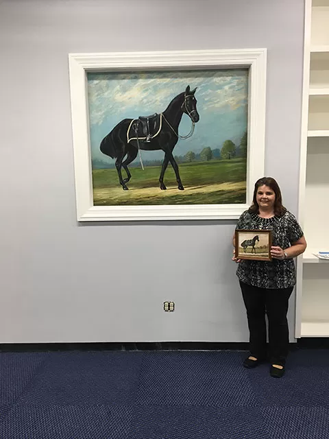 Former AOC employee Karen Livingston poses with the Blackjack painting while holding the painting it was based on.