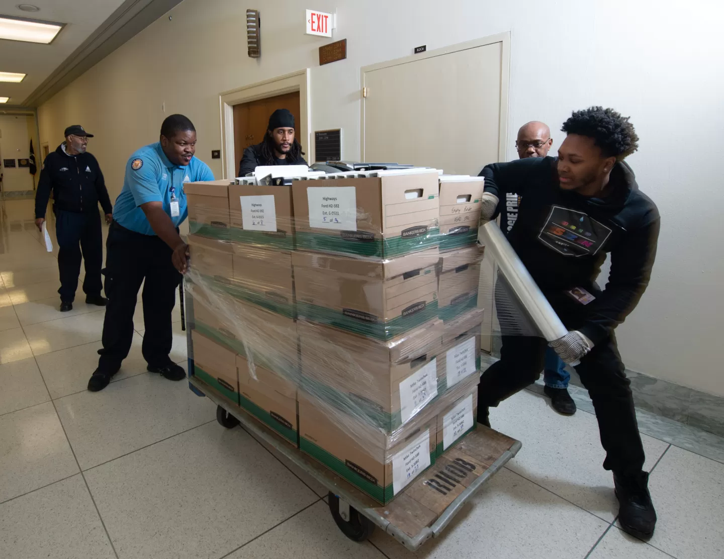 AOC House Office Buildings employees work together to shrink wrap boxes, ensuring a safe move.