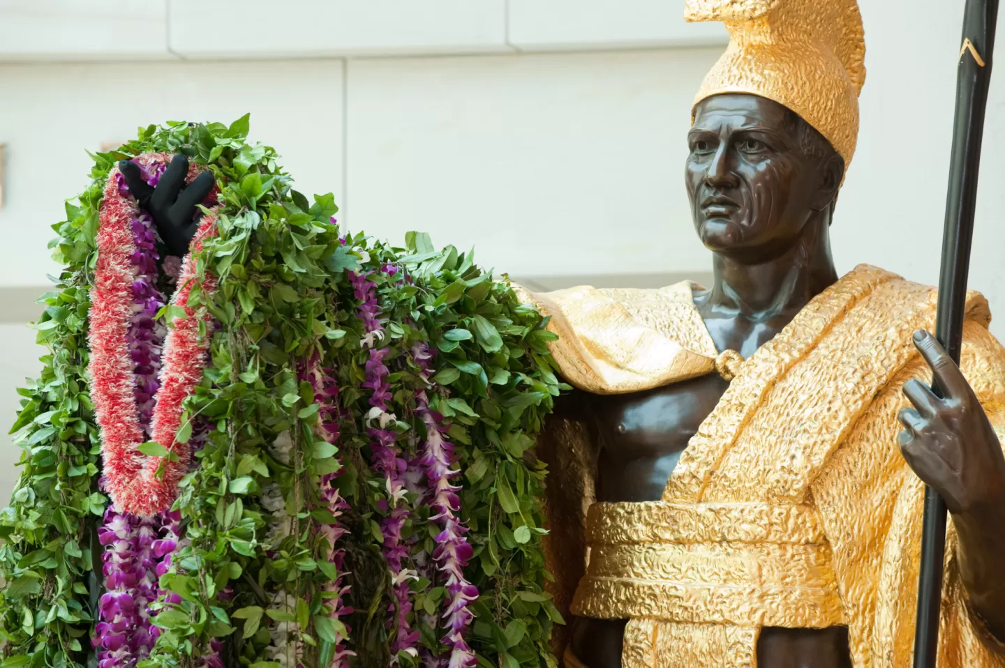Bronze statue of a person standing holding plants.