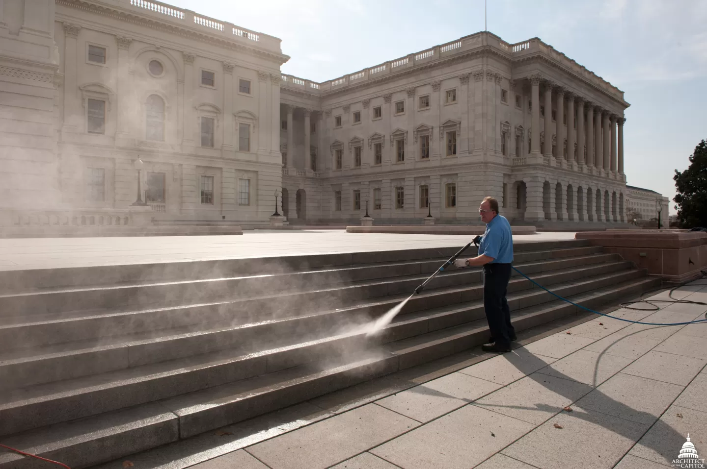 Person standing using a water sprayer.