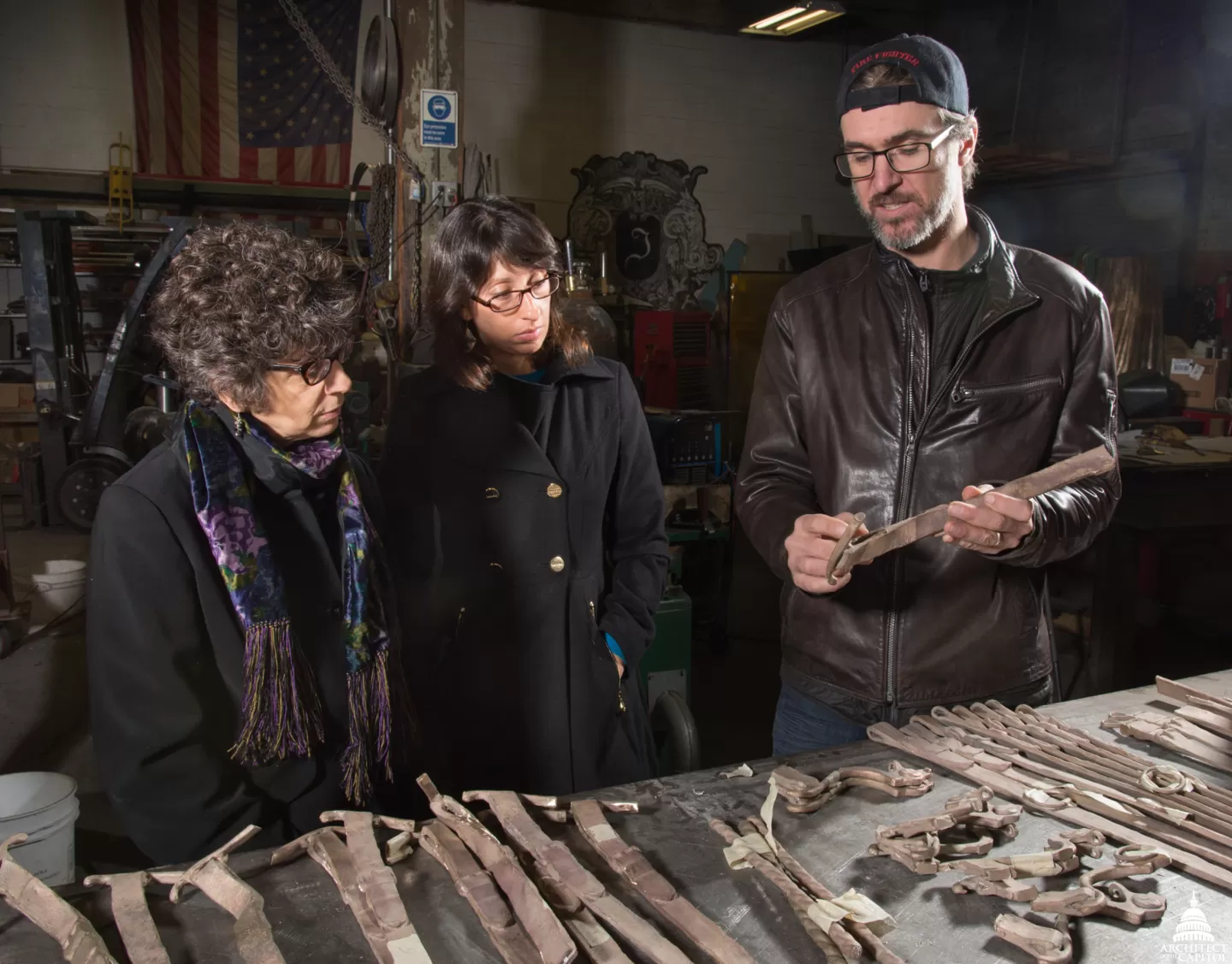 Three people looking at pieces of sculpture.