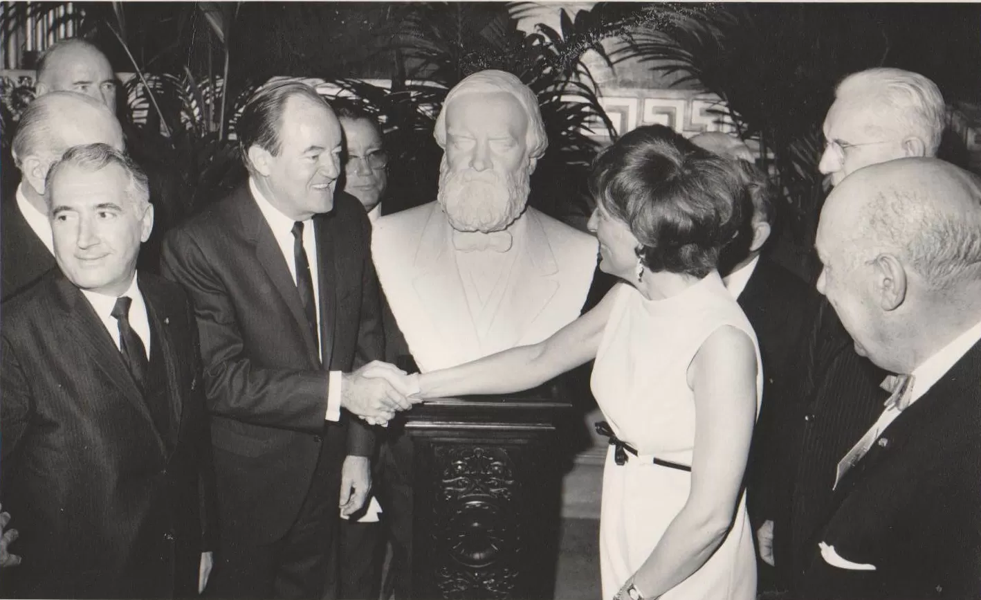 People standing around a bust.