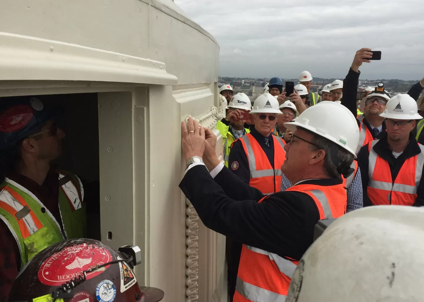 Group of people wearing safety vests and hard hats.