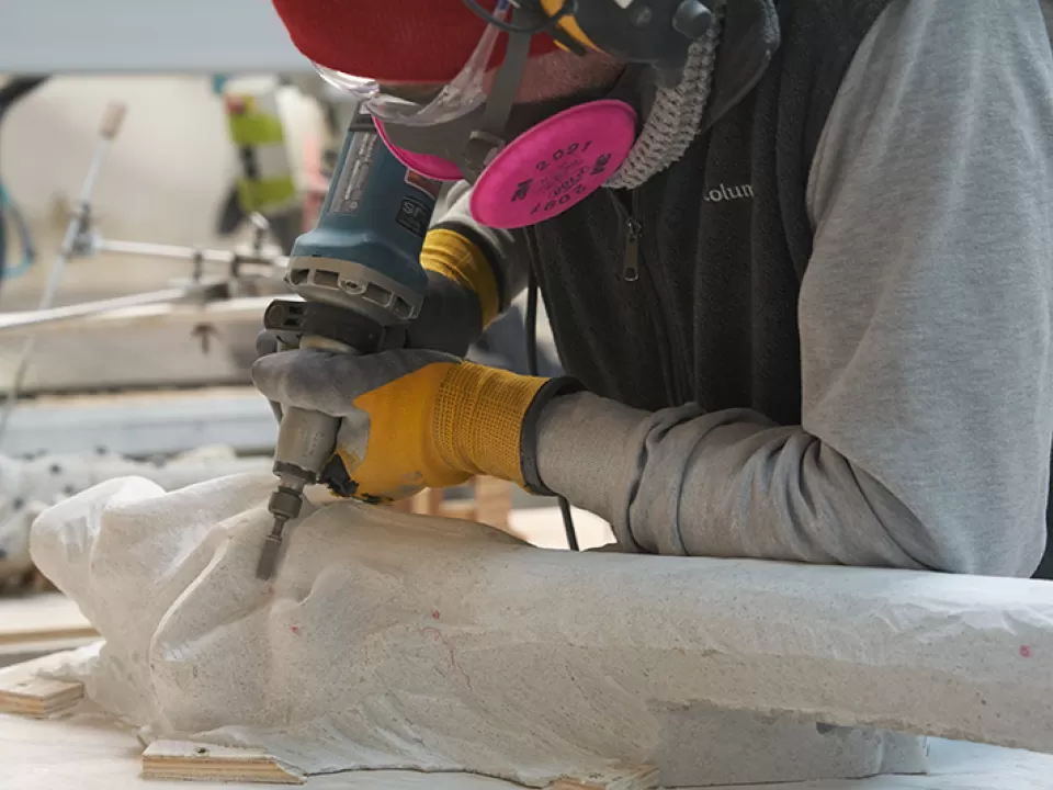 A worker carves a replica of the Genius's torch.