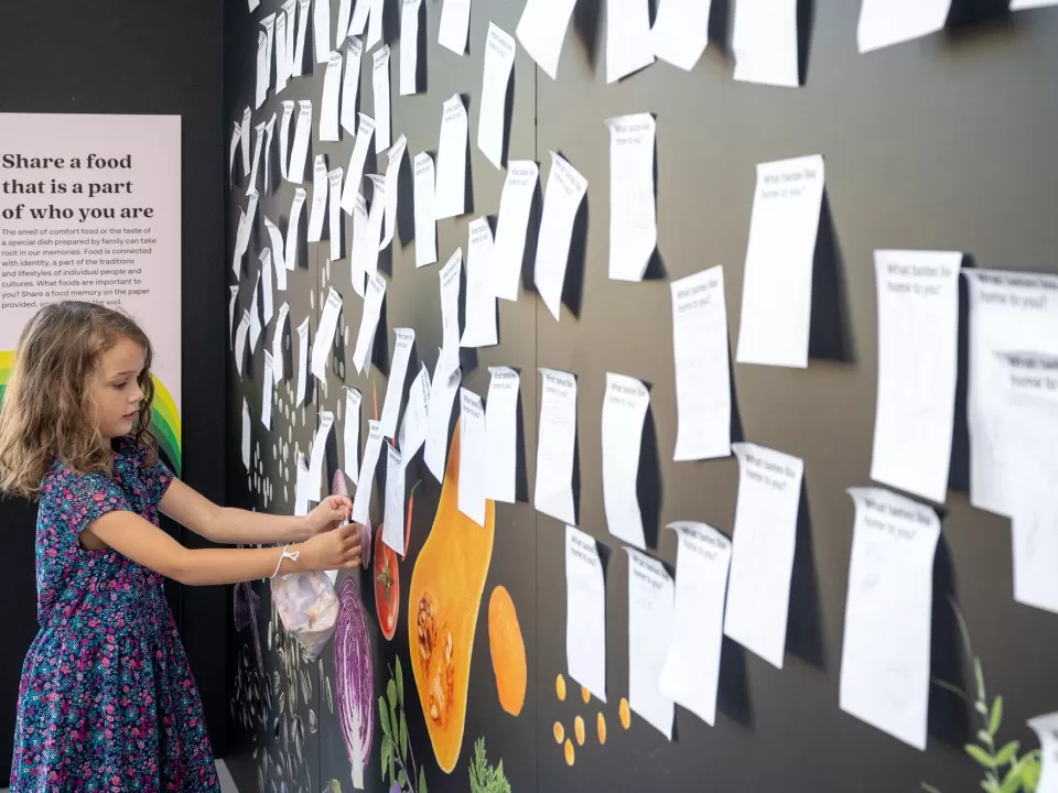 A young visitor adds her message to the What Tastes Like Home? wall.