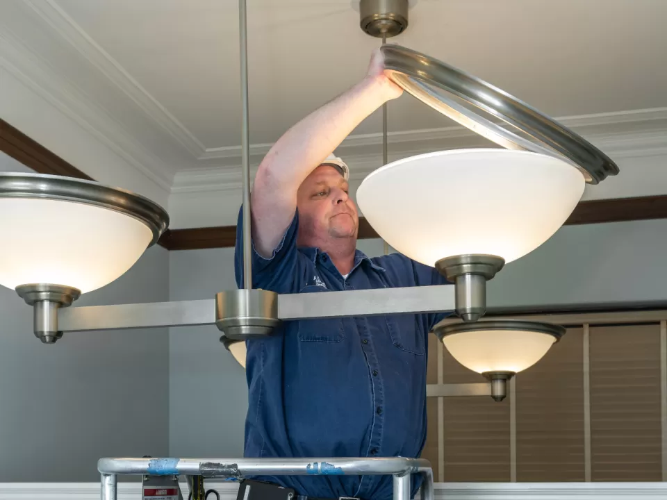 Brady Fleming, electrician leader with the Senate Electrical Branch, stands on a lift to adjust large lights in the Russell Building.