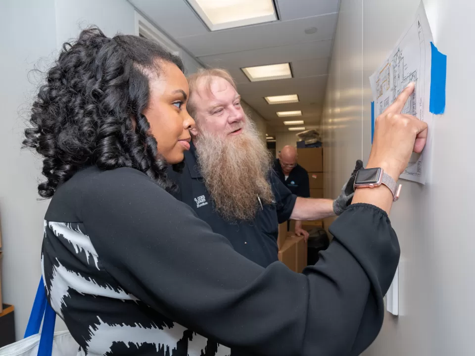 Senate Move Coordinator Alyssa Perron, who is also the energy engineer in the Senate buildings, discusses the suite’s furniture layout with Jerry Coats, material handler leader with the Senate Furniture Branch.