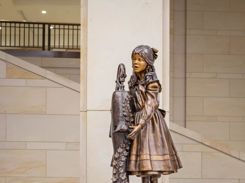 Bronze statue of child standing.