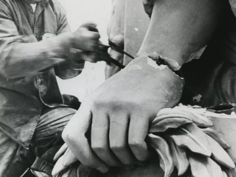 Person sawing off a portion of a statue.