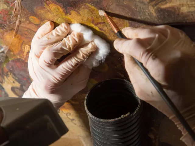 Hands working on a painting.