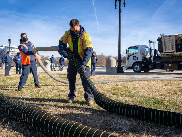 Mario Murgueitio and Ron Pfeiffer, both Pipefitters with Capitol Grounds, demonstrate how to use a mulch blower attachment to fill silt socks with mulch.