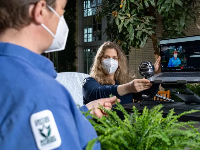 Grace Anderson adjusts the camera and laptop for an online horticultural education program.