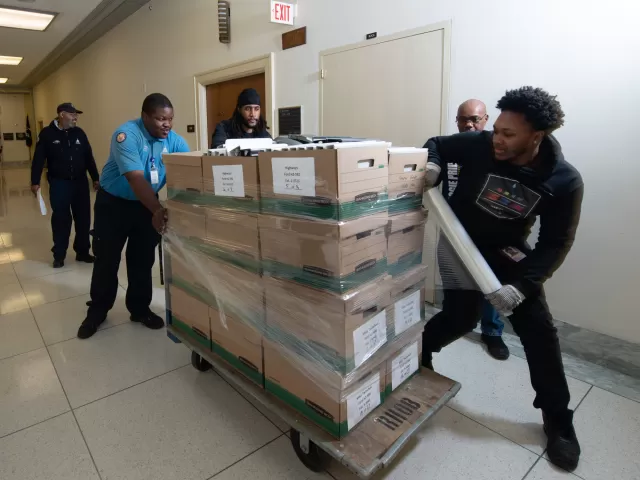 AOC House Office Buildings employees work together to shrink wrap boxes, ensuring a safe move.