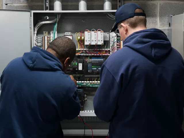 Two people looking at a control panel.