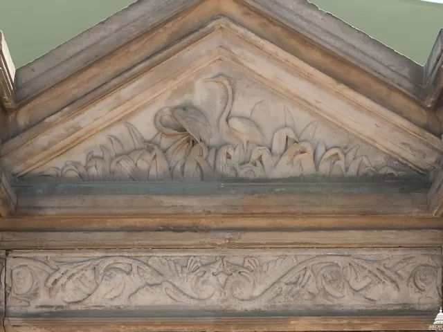 Blue heron carved in stone at the focal point, the central fountain, in the perimeter wall surrounding Capitol Square.