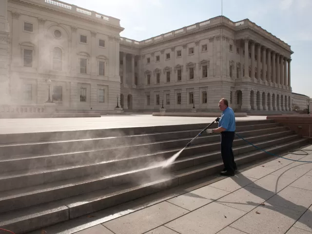 Person standing using a water sprayer.