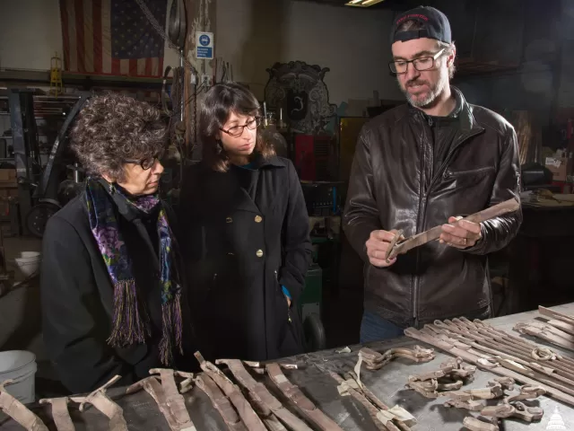 Three people looking at pieces of sculpture.